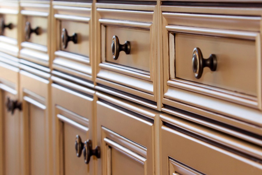 Close view of stained cabinet drawer fronts with dark bronze knobs
